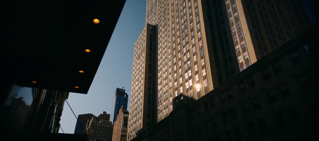 Tall buildings dominate the urban landscape with window facades that reflect sunlight under a clear blue sky