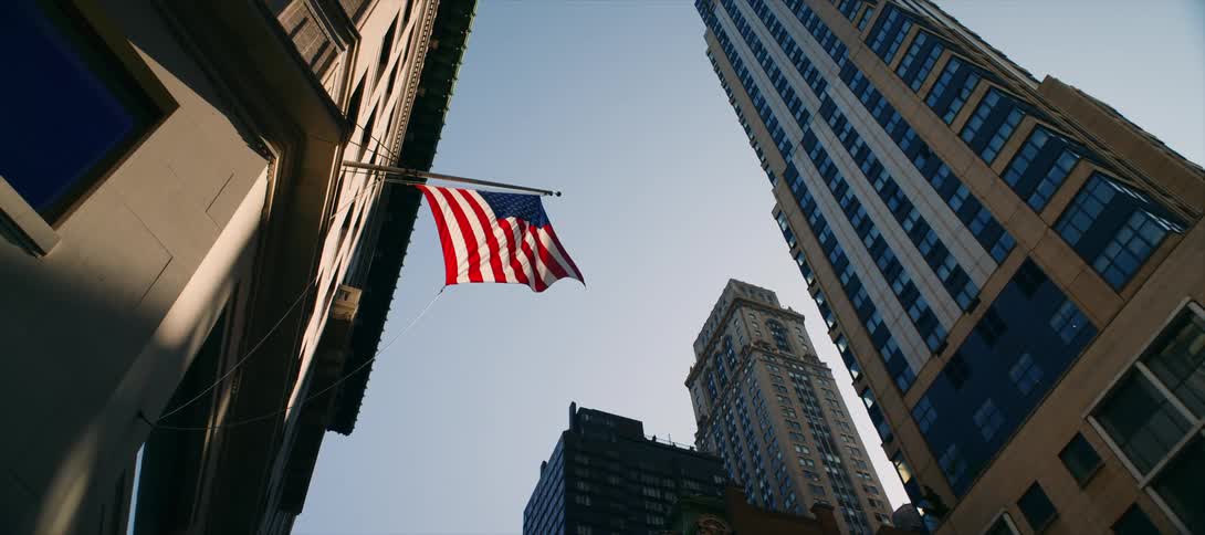 United states flag waves between tall buildings in the city center
