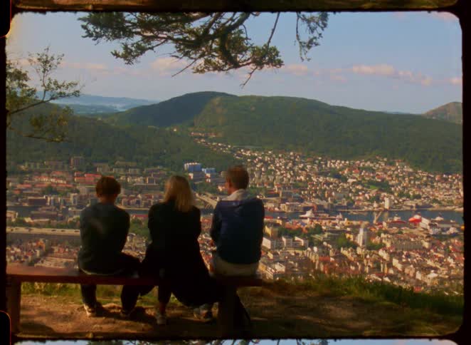 A family sits on a bench overlooking the city and mountains