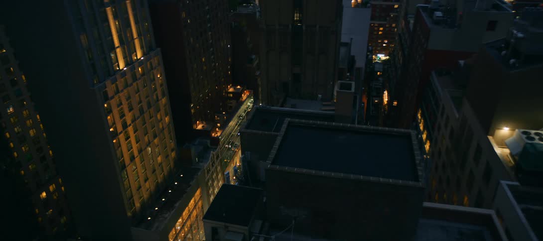 Aerial view of tall city buildings with glowing windows at night