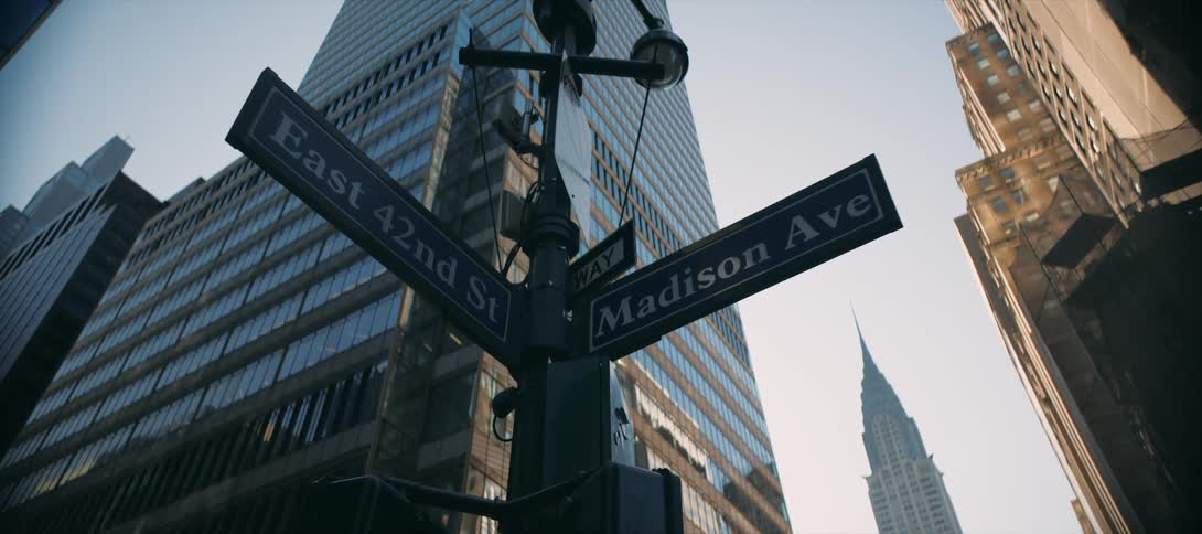 Street signs showing the intersection of east 42nd street and madison avenue in an urban area