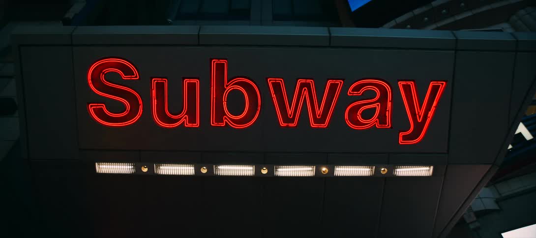 The video shows a closeup shot of a bright red neon sign that reads subway the sign is mounted on the side of a building and is framed against a dark night sky the watermark filmsupply is visible on the video