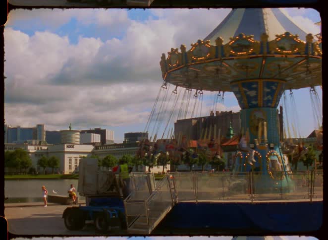People enjoy fun rides at carnival with a city skyline in the background