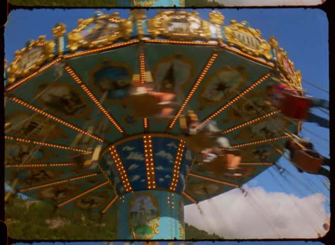 People ride a colorful swing carousel at a carnival