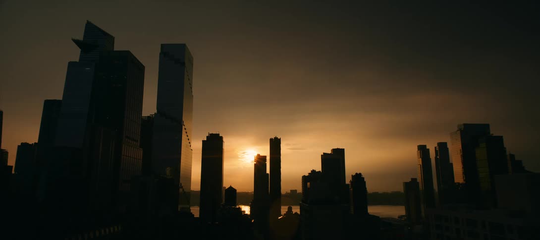 A city skyline is silhouetted against the sunset