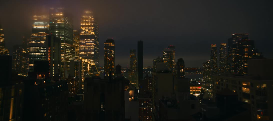 Fog drifts through glowing highrises across a dense nighttime skyline