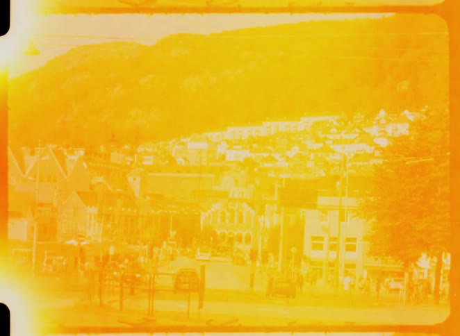 Busy street in a european city surrounded by houses with red roofs and a mountain in the background