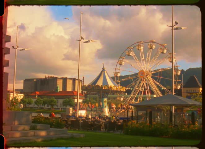 Ferris wheel and carousel in an amusement park at sunset