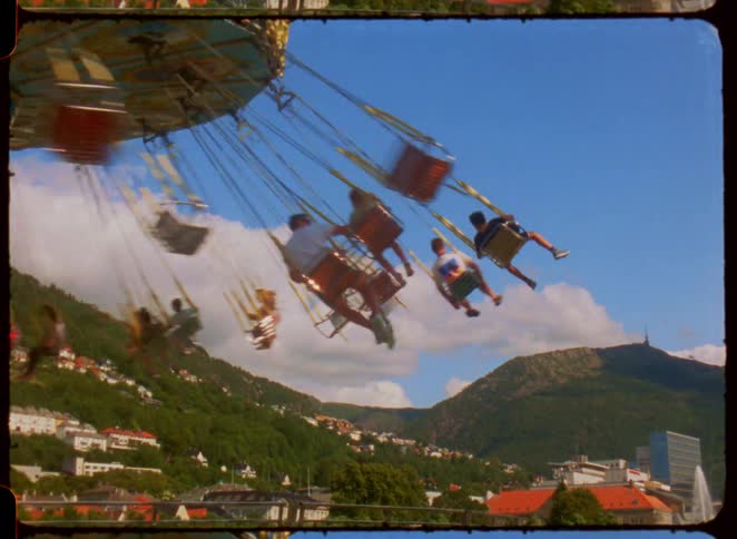 People enjoy a spinning amusement park ride with mountains in the background