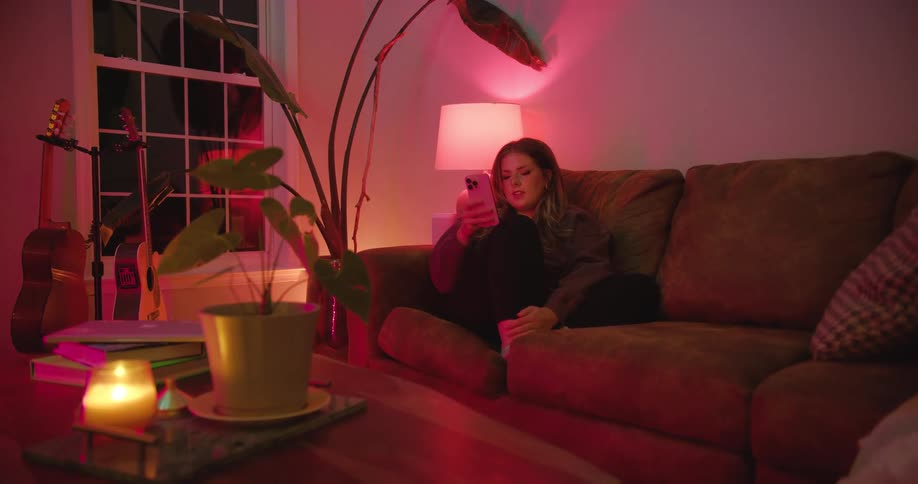 A woman sitting on a couch looks at the screen of her smartphone