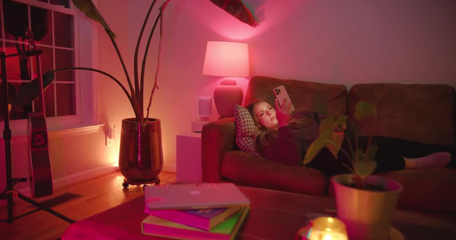 A woman reclining on a couch is looking at her smart phones screen