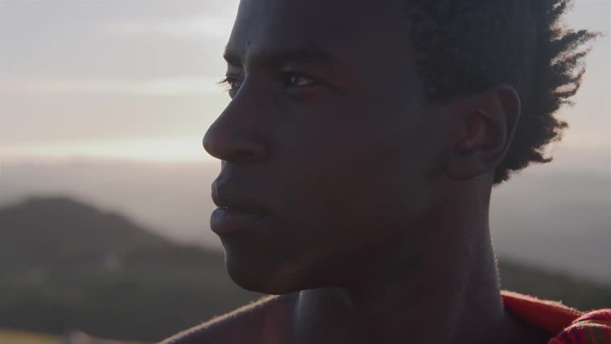 A mans face is staring to the right and behind him is a strong flare of sunlight