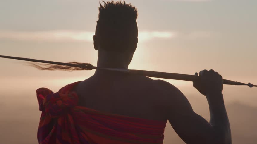 The man holds a spear on his shoulder
