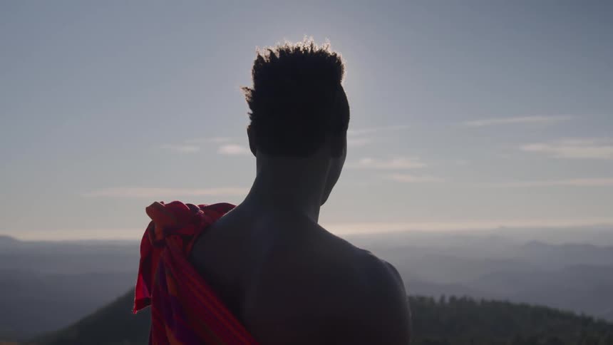 The man stands on the mountain looking at the horizon
