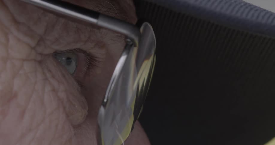 An elderly man looks through glasses