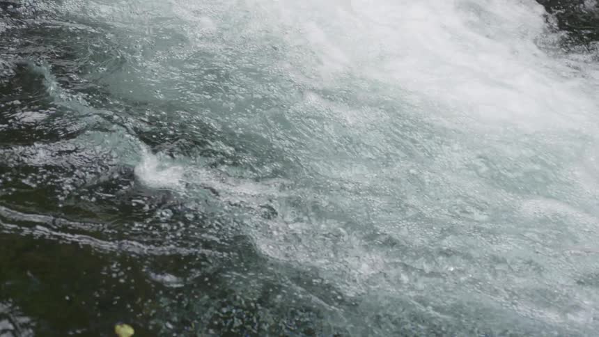 The video shows a closeup shot of a fastmoving white water river the camera is very close to the surface showing the churning and bubbling of the water as it rushes over unseen rocks