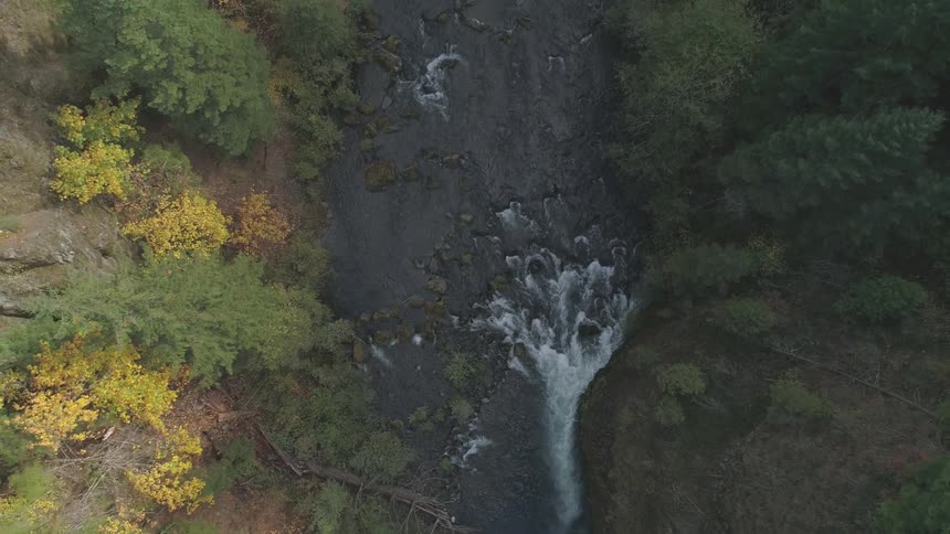 An aerial view of a river that has some rocks in the path making a huge current