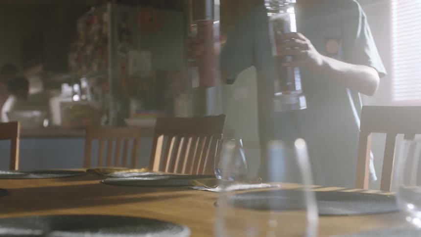 A person places salt and pepper grinders on a dining table