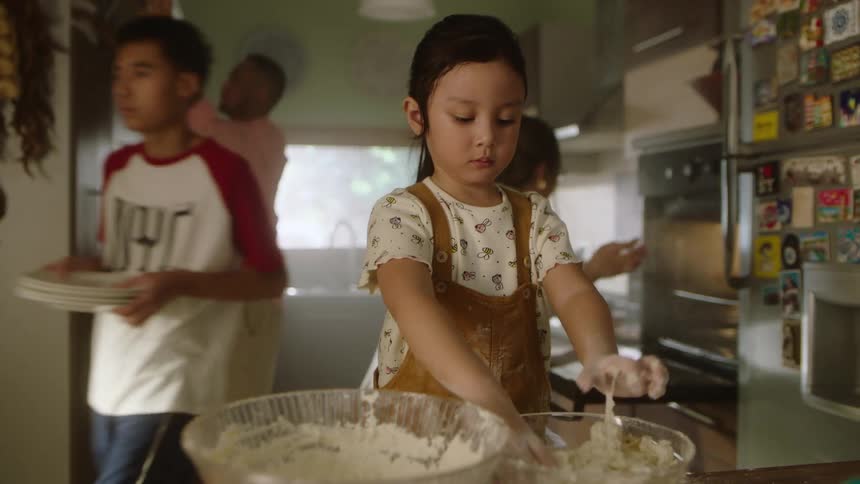 Family gathered in the kitchen with a child playing with dough