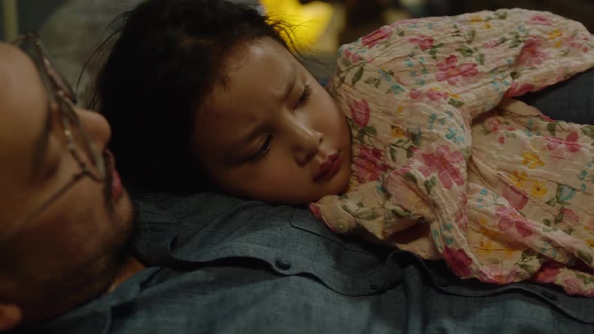 Father and daughter cuddle during a bedtime story at night