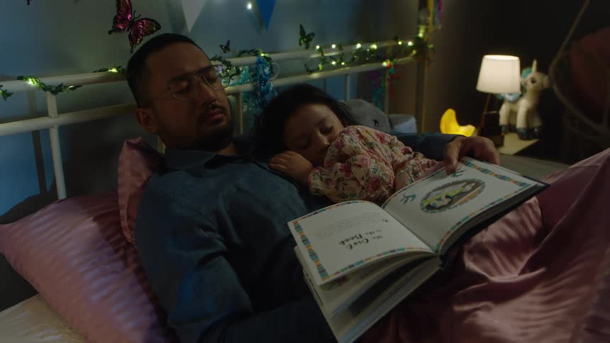 Father and daughter sleep having fallen asleep in the middle of reading a bedtime story