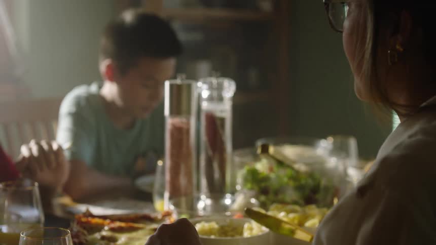 A family eating lunch together at the dining table with the mother and two sons talking during the meal