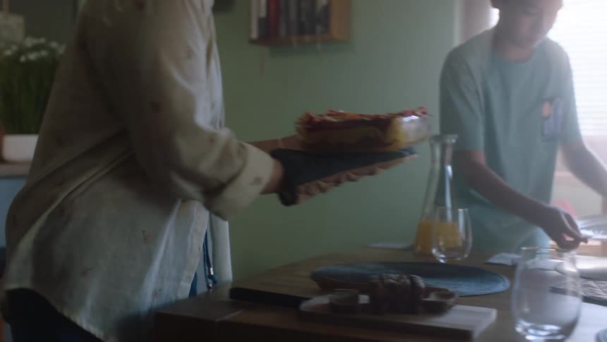 A woman serves a platter of food to the dining table