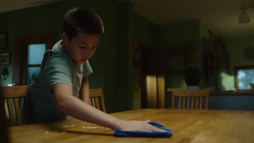 Two teenage boys clearing a dining table after a meal