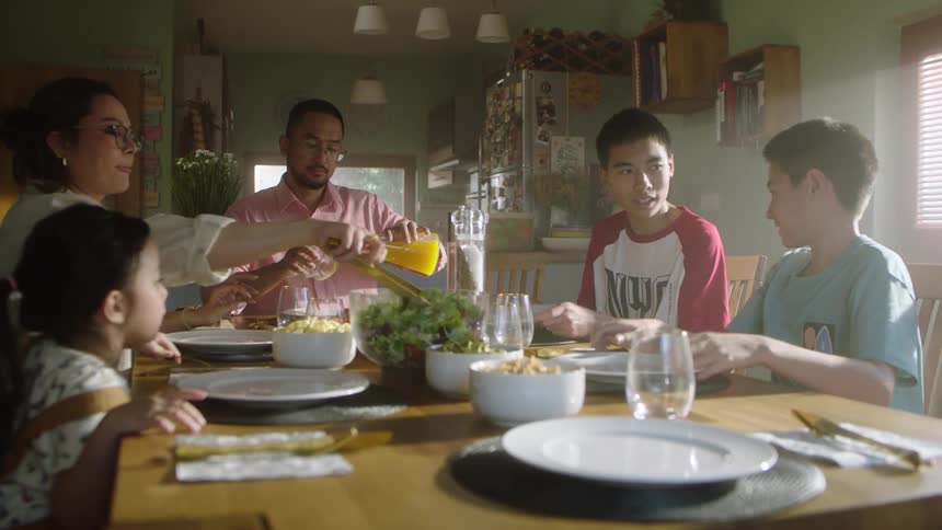 A family gathers around the dining table sharing a meal together