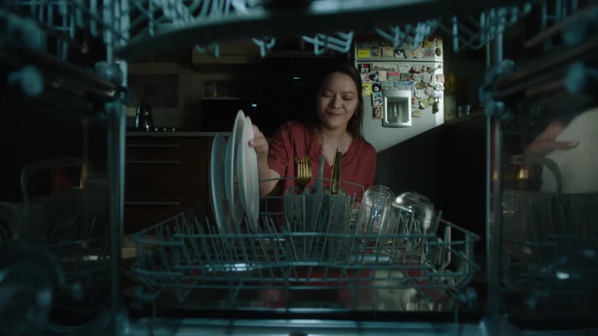 The woman removes the dishes from the dishwasher
