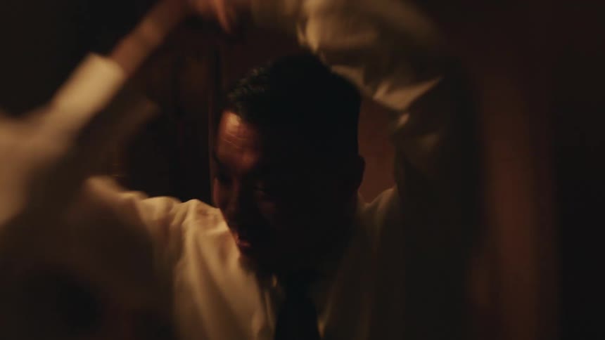 A couple is dancing and laughing together in a dimly lit room the man twirls the woman and she smiles as she spins