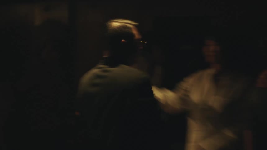 A couple is dancing slowly in a dimly lit room the man is holding the woman close as they sway together