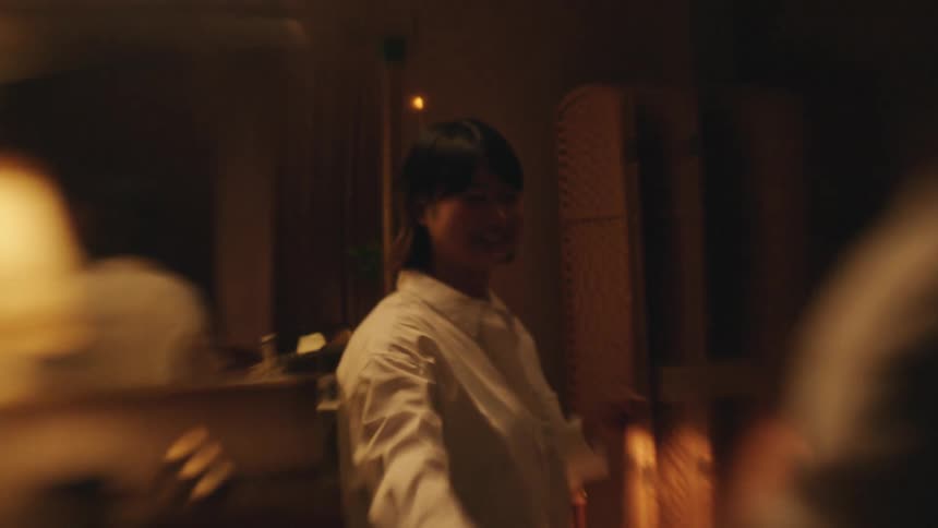 A man and woman are seen in a dimly lit room joyfully dancing together and laughing as the man twirls the woman