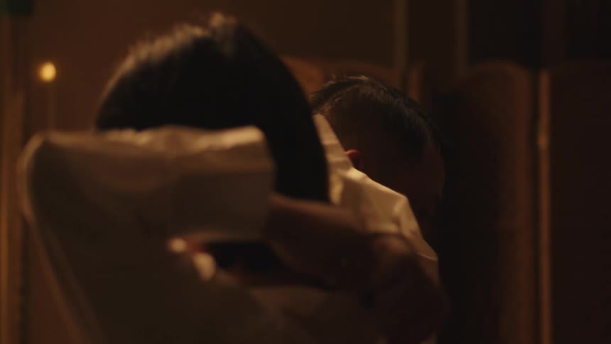 A couple dances closely and happily in a dimly lit room