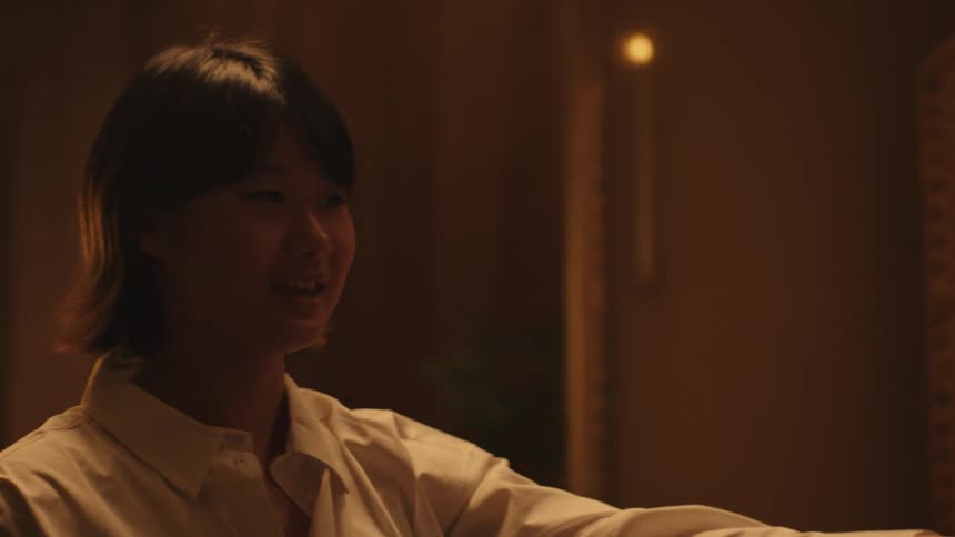 A man and woman are joyfully dancing together in a dimly lit room with the man twirling the woman as they both smile and laugh