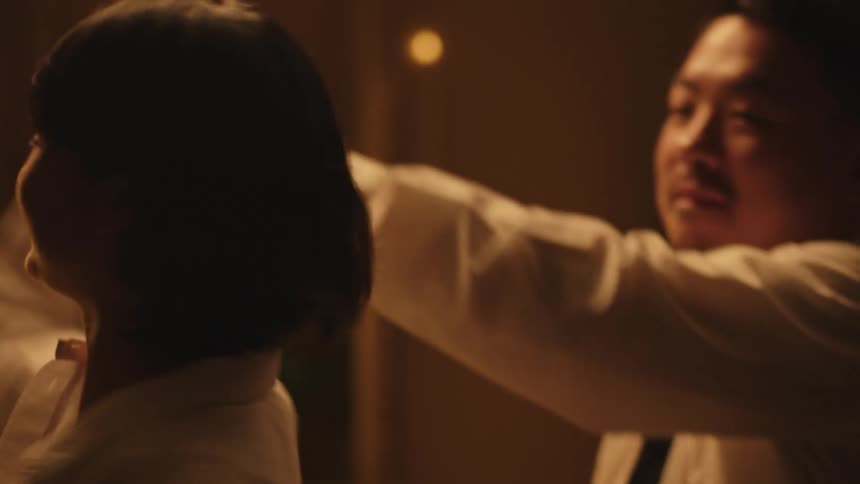 A couple is seen laughing and joyfully dancing together in a dimly lit room with the man twirling the woman