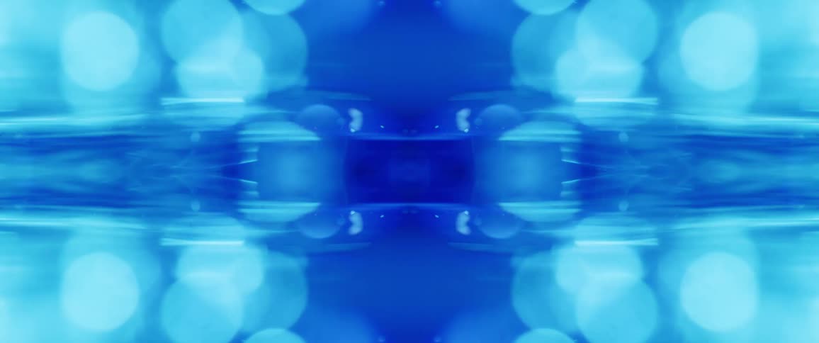 A blurred abstract symmetrical image is composed of light and dark blue circles and shapes with horizontal streaks of light