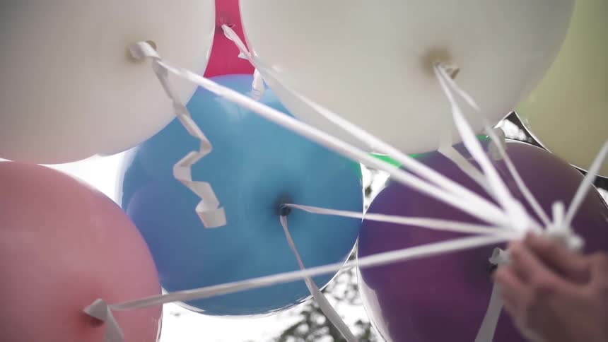 A hand holds helium balloons