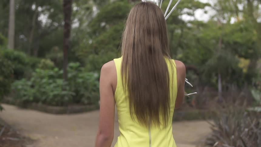 Woman walks down a path holding something in the air