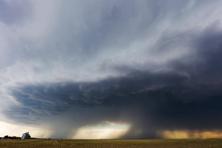 Dark clouds covering the sky over the countryside at midday signaling an approaching storm with a shelter sitting on a grass field