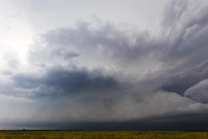 Dark storm clouds flow and rotate above a rural landscape during the daytime