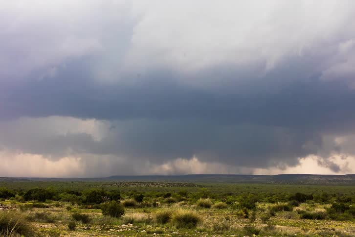 Storm clouds gather and spin over a grass field