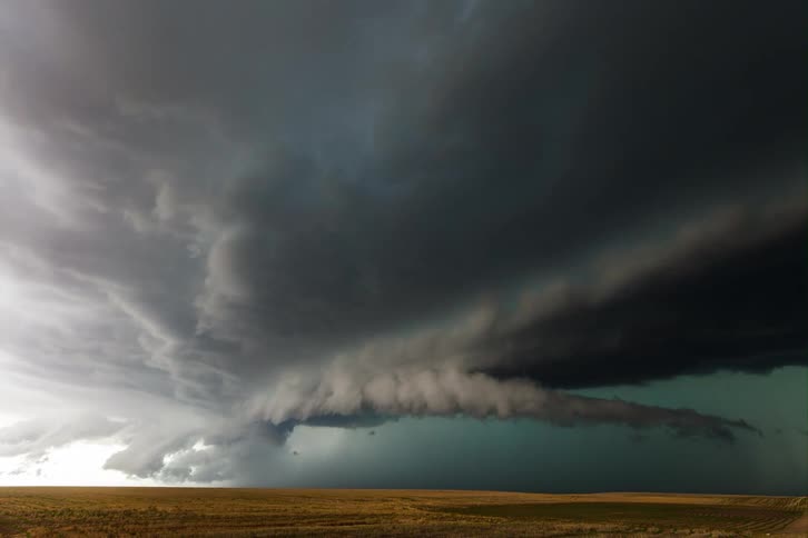 Dark clouds forming in the sky signaling an approaching storm over a wide stretch of land at midday