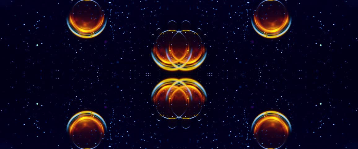 A dark background filled with glowing dots forms a pattern around a central orange and yellow symmetrical light that expands and contracts