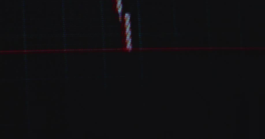 Hectical macro shot with hand held camera movement of a financial candlestick trading chart crashing down into the red digits causing panic sales and fear of a recession or a rug pull as investors lose all of their money to online scammers