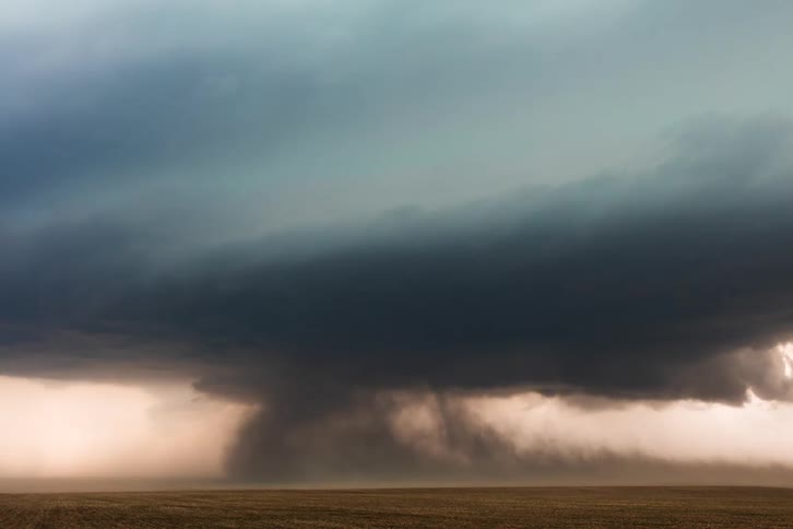 The large rain clouds spin and wind moves on the field