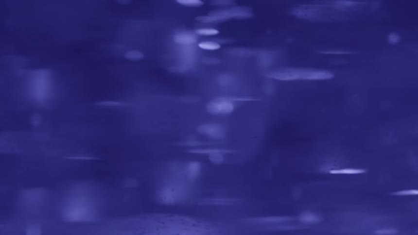 Blue liquid in motion with reflections and suspended particles