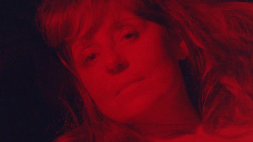 The woman is laying down under the red light