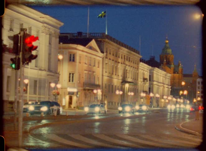 Cars drive along a city street at night
