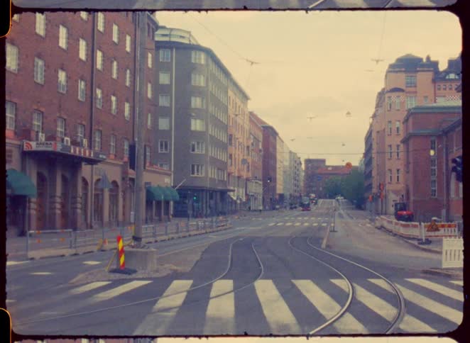 Empty streets with tram tracks cross an avenue lined with old buildings